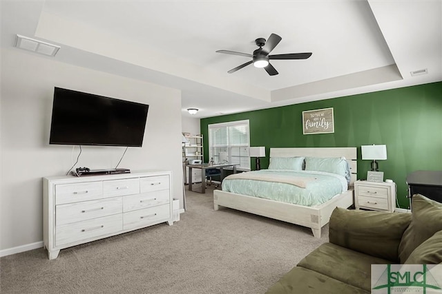 bedroom featuring ceiling fan, light carpet, and a tray ceiling