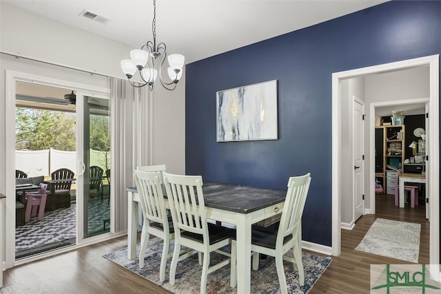 dining area with dark hardwood / wood-style flooring and an inviting chandelier