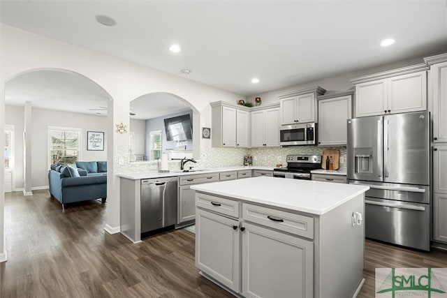 kitchen featuring gray cabinets, stainless steel appliances, a kitchen island, and dark wood-type flooring