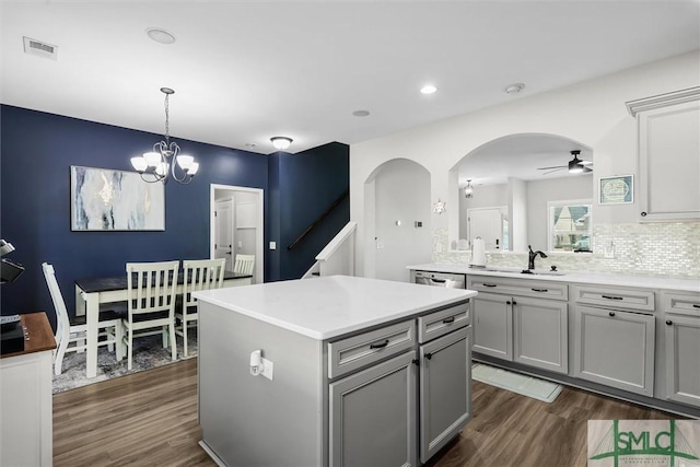 kitchen with a center island, backsplash, ceiling fan with notable chandelier, sink, and gray cabinets