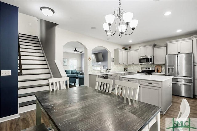 dining space with ceiling fan with notable chandelier, dark hardwood / wood-style floors, and sink