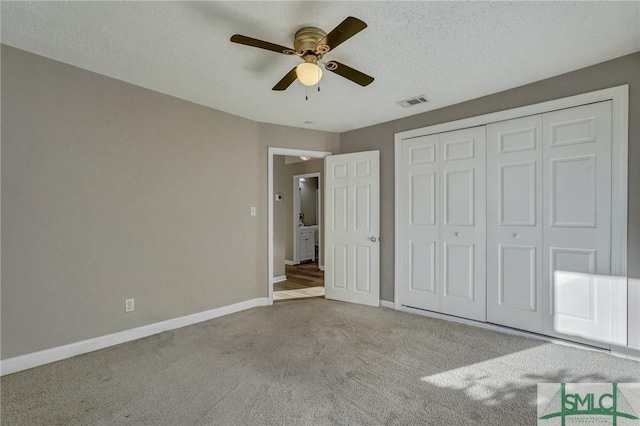 unfurnished bedroom featuring ceiling fan, light colored carpet, a textured ceiling, and a closet