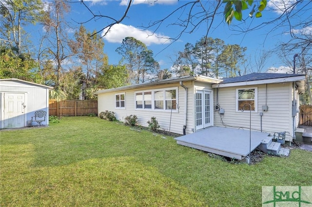 rear view of property featuring french doors, a yard, and a storage unit