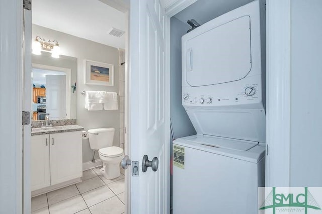 clothes washing area with light tile patterned flooring, sink, and stacked washer and dryer