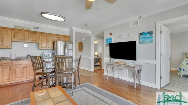 kitchen featuring ceiling fan, ornamental molding, light brown cabinetry, and stainless steel refrigerator