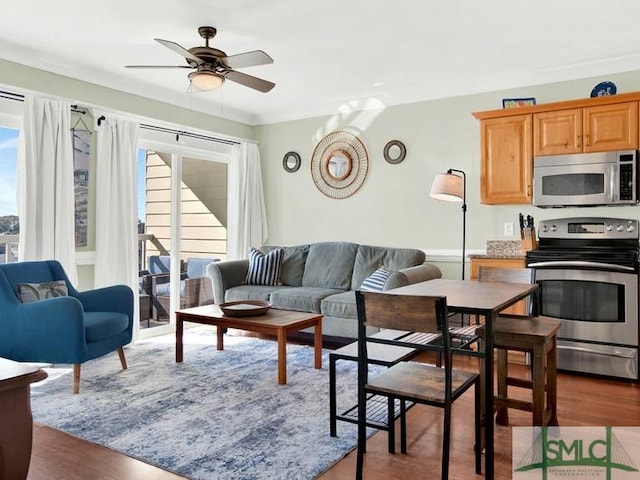 living room with ornamental molding, ceiling fan, and dark wood-type flooring