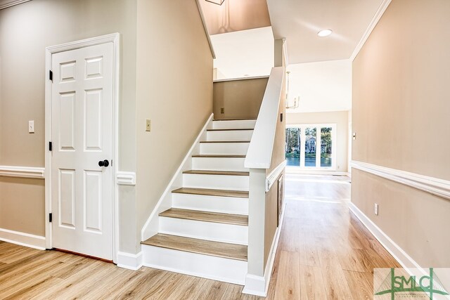 stairs with hardwood / wood-style floors and ornamental molding