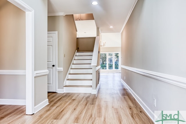 stairs with hardwood / wood-style floors and ornamental molding