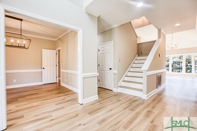 interior space with wood-type flooring, ornamental molding, and an inviting chandelier