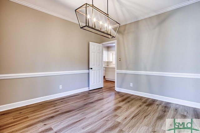 unfurnished dining area with ornamental molding, light wood-type flooring, and a notable chandelier