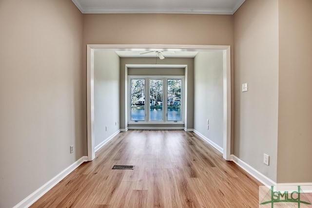 empty room featuring light wood finished floors, baseboards, a ceiling fan, and ornamental molding