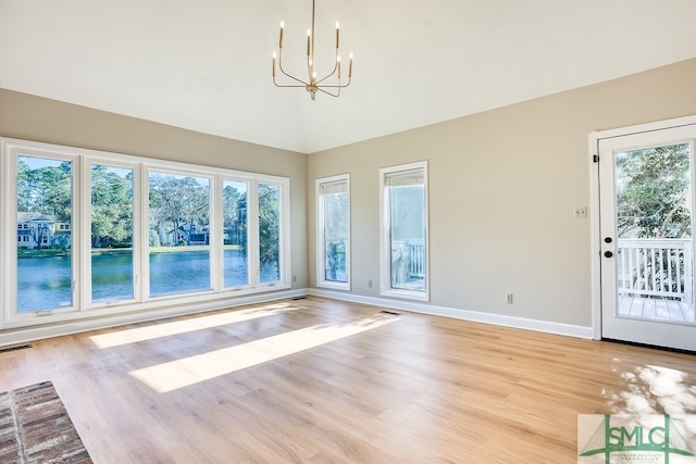 unfurnished living room featuring a chandelier, lofted ceiling, and light wood-style floors