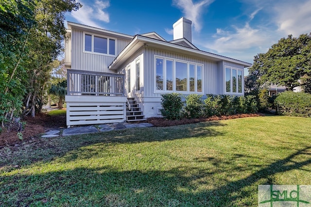 rear view of property with stairs, a chimney, a deck, and a lawn