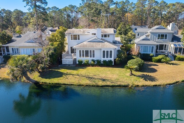 rear view of house with a water view and a lawn