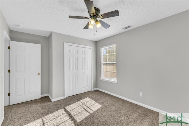 unfurnished bedroom with carpet flooring, ceiling fan, a textured ceiling, and a closet