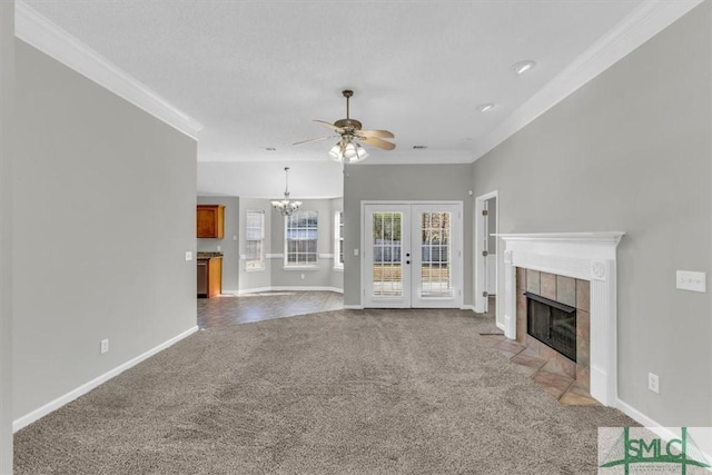 unfurnished living room featuring carpet flooring, crown molding, a fireplace, and ceiling fan with notable chandelier