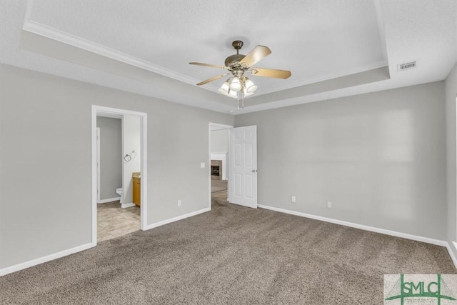 unfurnished bedroom featuring ceiling fan, a raised ceiling, and ensuite bathroom