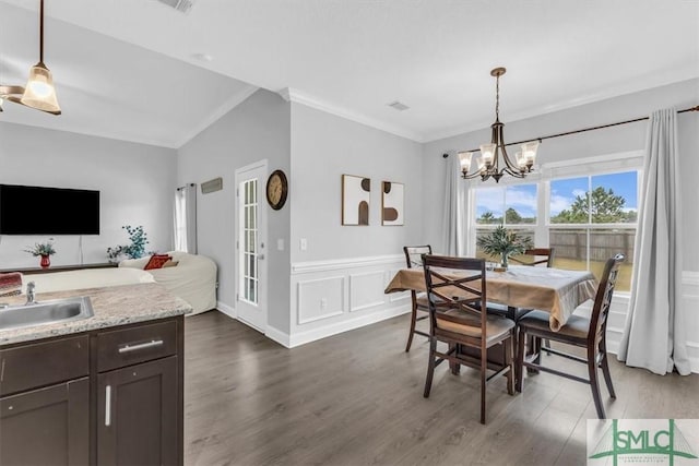 dining area featuring an inviting chandelier, sink, dark wood-type flooring, and ornamental molding