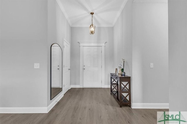 entrance foyer with crown molding, an inviting chandelier, and light wood-type flooring