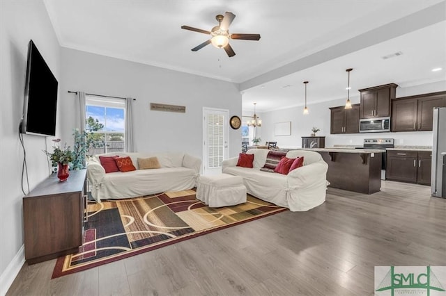 living room with crown molding, ceiling fan with notable chandelier, and light hardwood / wood-style floors