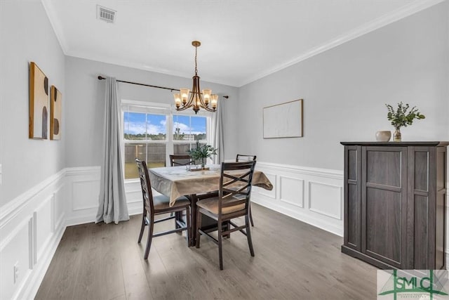 dining area with an inviting chandelier, wood-type flooring, and crown molding