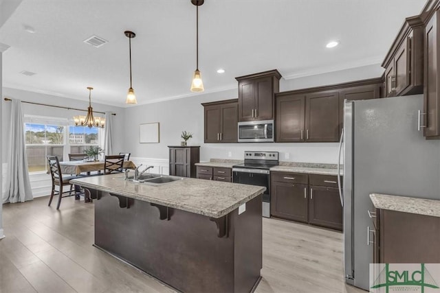 kitchen featuring pendant lighting, sink, crown molding, an inviting chandelier, and stainless steel appliances