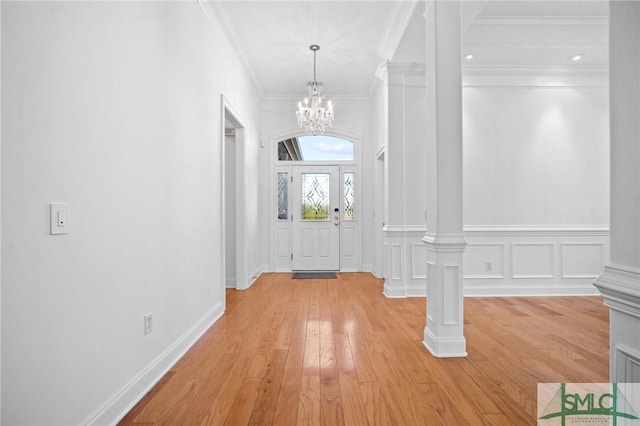 entrance foyer with light wood-type flooring, ornate columns, and an inviting chandelier