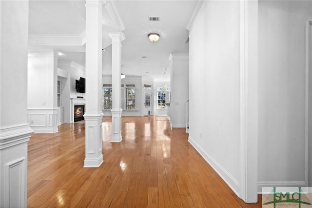 foyer entrance featuring crown molding, ornate columns, and light hardwood / wood-style floors