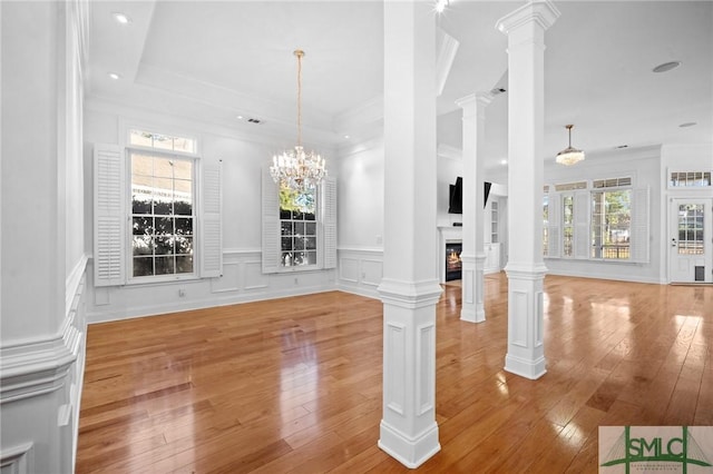 unfurnished dining area featuring ornate columns, crown molding, and light hardwood / wood-style floors