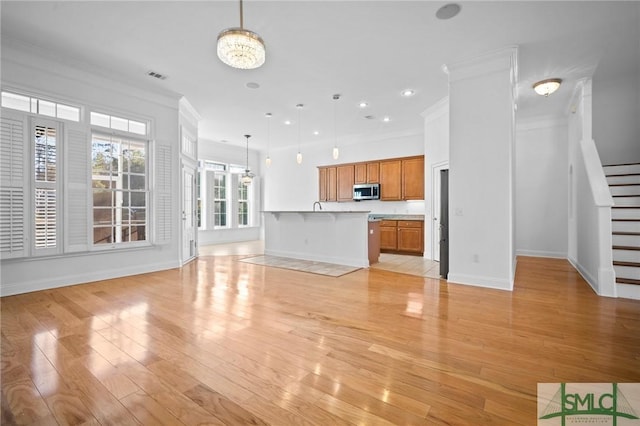 unfurnished living room featuring a notable chandelier, light hardwood / wood-style floors, and ornamental molding