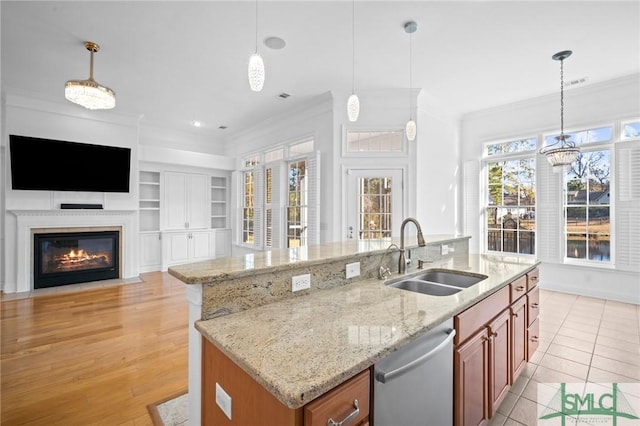 kitchen featuring stainless steel dishwasher, sink, pendant lighting, and a center island with sink