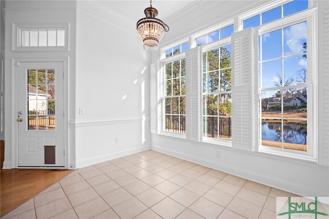 unfurnished sunroom featuring a notable chandelier, a water view, and a wealth of natural light