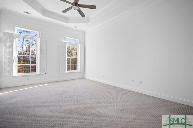 carpeted empty room featuring a tray ceiling, ornamental molding, ceiling fan, and a wealth of natural light