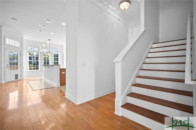 stairs featuring wood-type flooring and ornamental molding