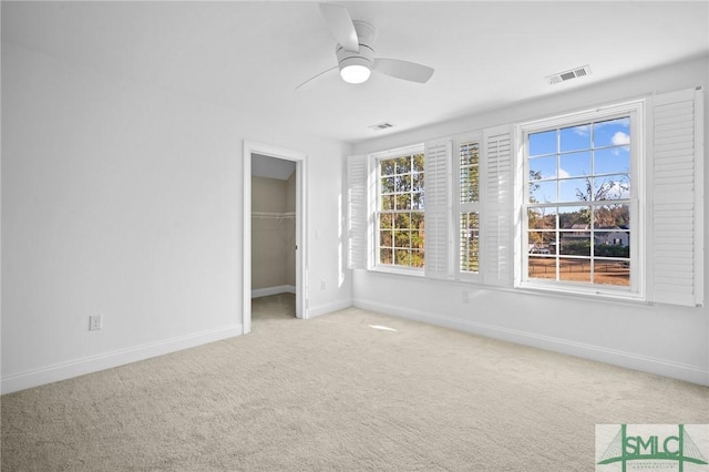 unfurnished bedroom featuring ceiling fan, a closet, a walk in closet, and carpet flooring