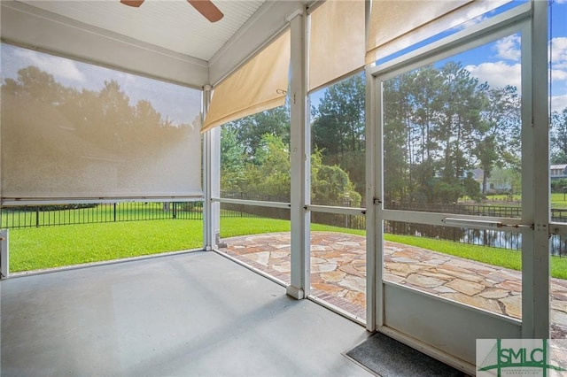 unfurnished sunroom with a water view and ceiling fan