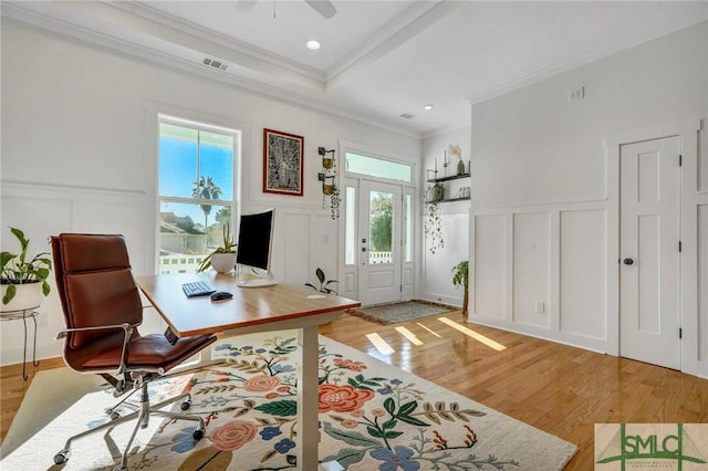 office area featuring a raised ceiling, crown molding, ceiling fan, and light hardwood / wood-style floors