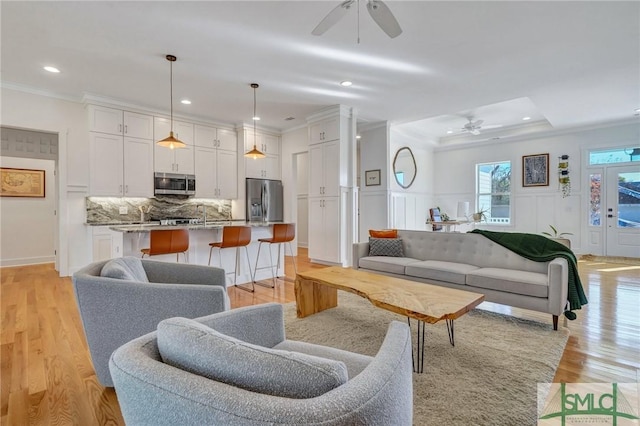 living room featuring light hardwood / wood-style flooring, ornamental molding, and ceiling fan