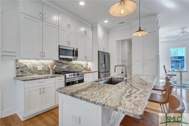 kitchen featuring appliances with stainless steel finishes, sink, white cabinets, and a kitchen bar