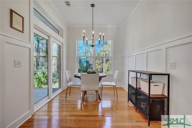 dining room featuring hardwood / wood-style flooring, a wealth of natural light, ornamental molding, and a chandelier