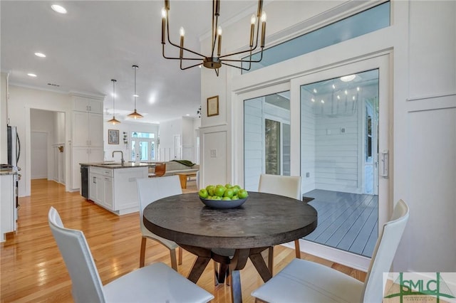 dining area featuring sink, a chandelier, and light wood-type flooring