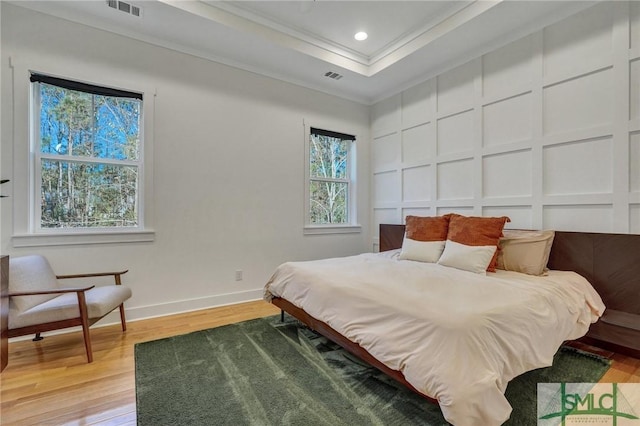 bedroom featuring crown molding, wood-type flooring, and a tray ceiling