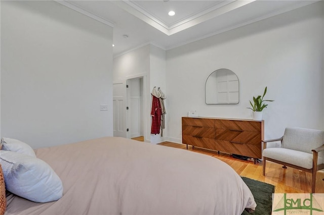 bedroom featuring a tray ceiling, wood-type flooring, and ornamental molding