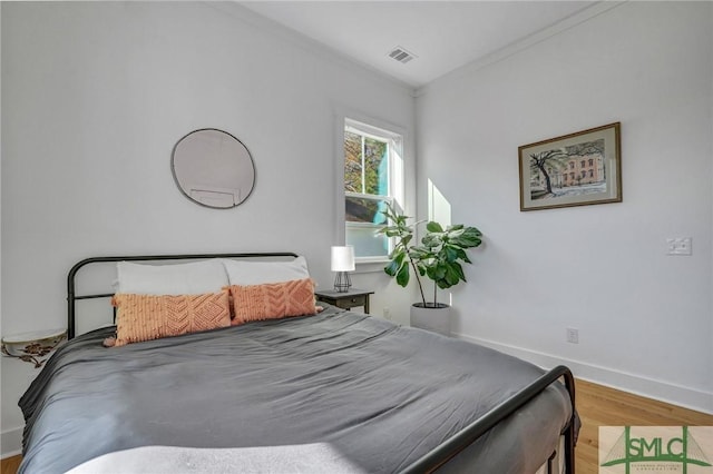 bedroom featuring crown molding and light hardwood / wood-style floors