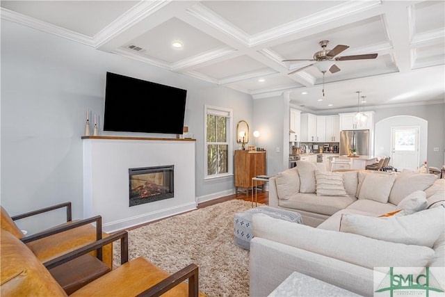 living room featuring coffered ceiling, crown molding, ceiling fan, beamed ceiling, and wood-type flooring