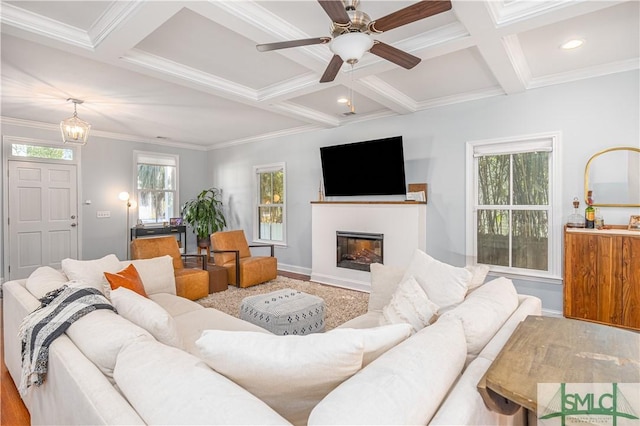 living room featuring beam ceiling, ornamental molding, ceiling fan, and coffered ceiling