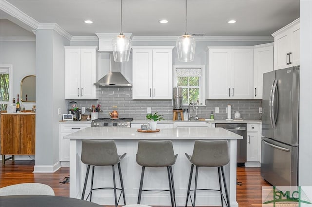 kitchen featuring a center island, sink, wall chimney exhaust hood, white cabinetry, and stainless steel appliances