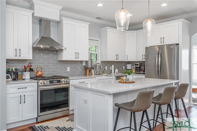 kitchen featuring a center island, stainless steel appliances, white cabinetry, and wall chimney exhaust hood