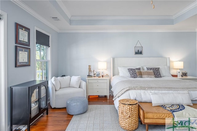 bedroom with dark hardwood / wood-style flooring, a tray ceiling, and crown molding