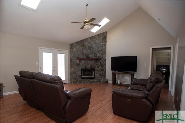 living room with ceiling fan, french doors, a stone fireplace, high vaulted ceiling, and wood-type flooring